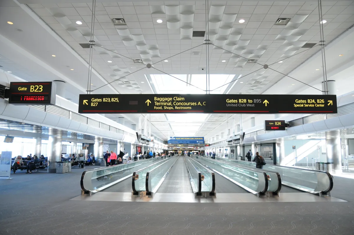 A bustling interior space with moving walkways, clear wayfinding signs, and comfortable seating areas. The image conveys a sense of travelers arriving and departing, emphasizing ease of access and connectivity. Various families and individuals can be seen moving through, highlighting the welcoming, family-oriented atmosphere.