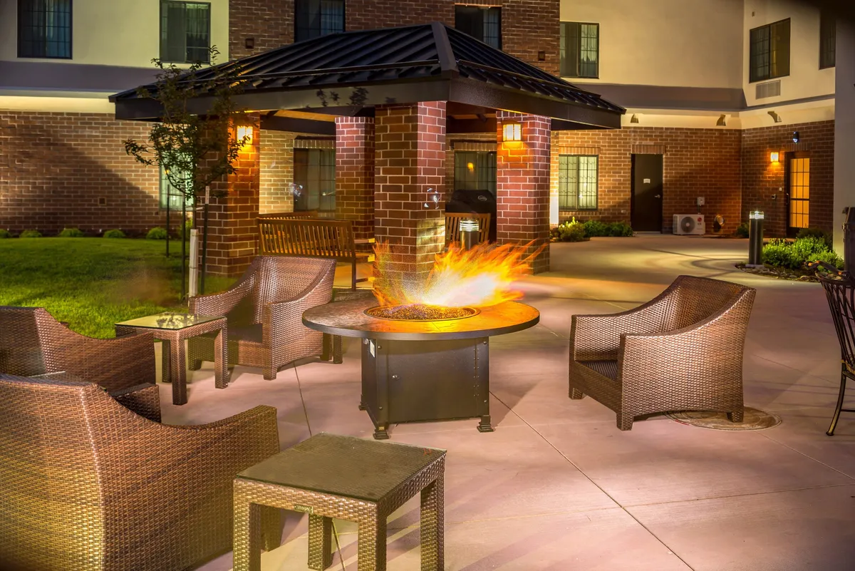 An inviting outdoor fire pit surrounded by comfortable seating and brick columns. The area is designed for relaxation, socializing, and informal gatherings, with a warm, welcoming ambiance that extends the idea of unwinding after a productive business day.